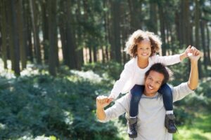Father carrying young daughter on his shoulders